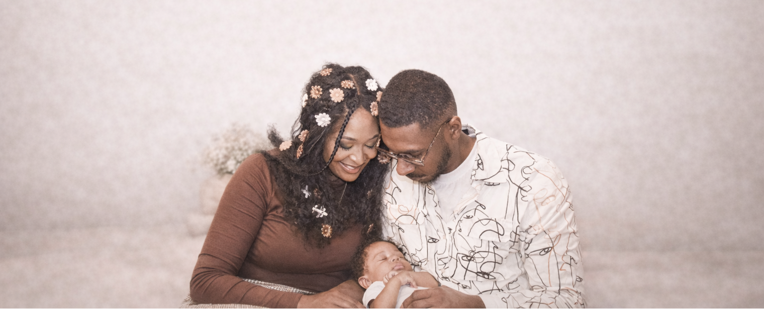 Couple holding a baby against a plain background